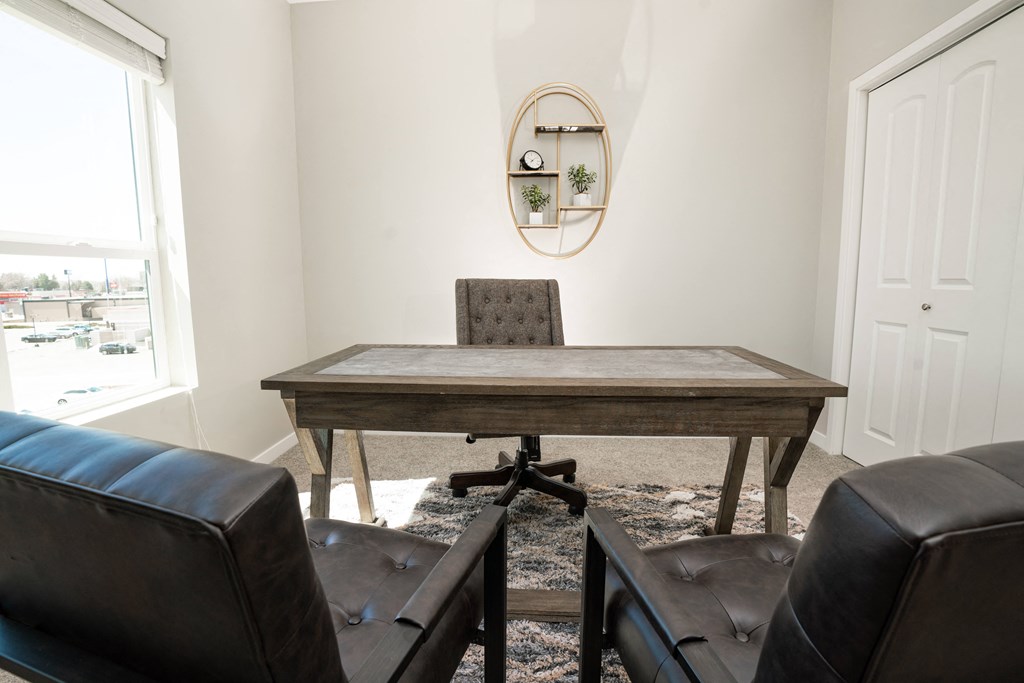 a home office with a large wooden desk and leather chairs