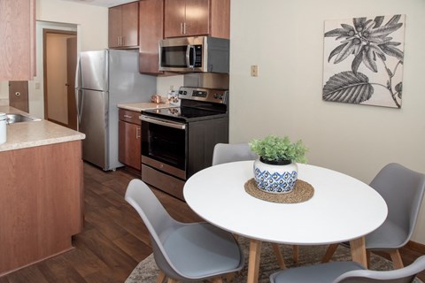 a kitchen with stainless steel appliances and a white table with chairs