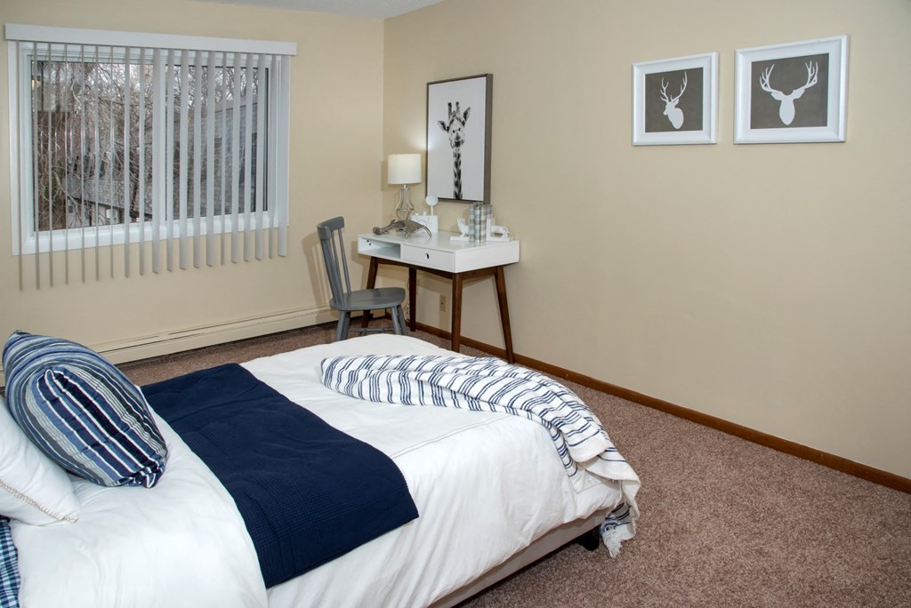 a bedroom with a bed and a desk and a window