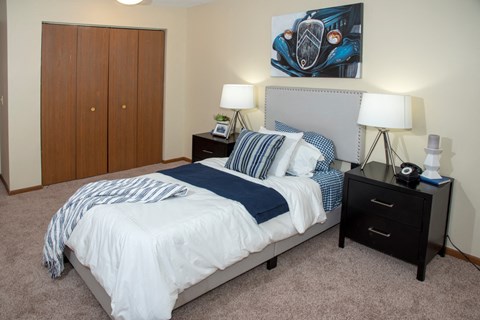 a bedroom with a bed and two night stands and a closet