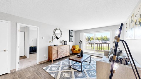 A living room with a wooden floor and a large window.