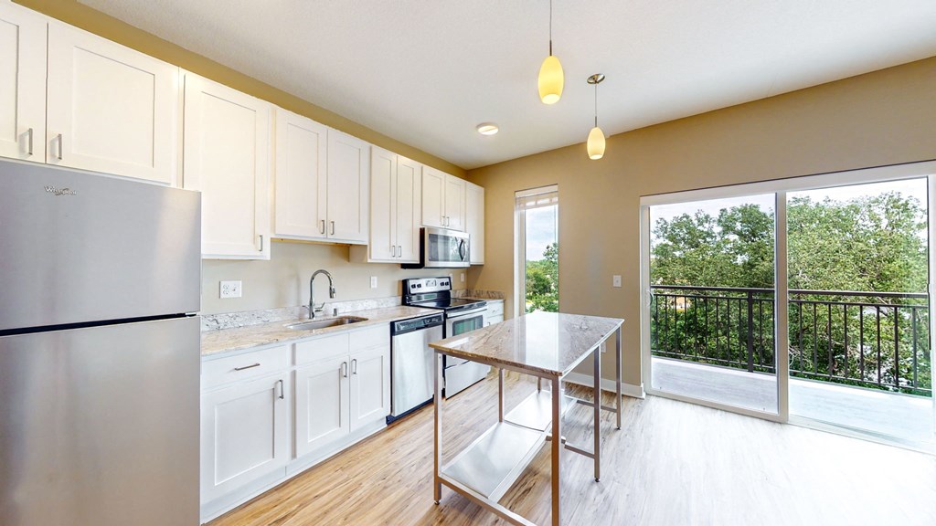 a kitchen with white cabinets and stainless steel appliances and a balcony