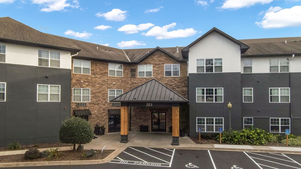 A building with a black roof and a parking lot in front.