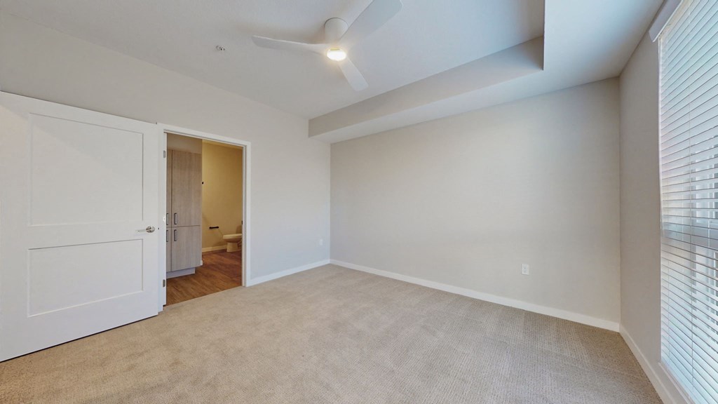 a spacious living room with white walls and a door to a bathroom