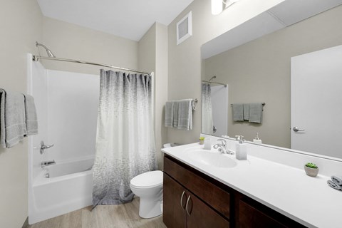 A bathroom with a white sink, toilet, and bathtub with grey shower curtain.