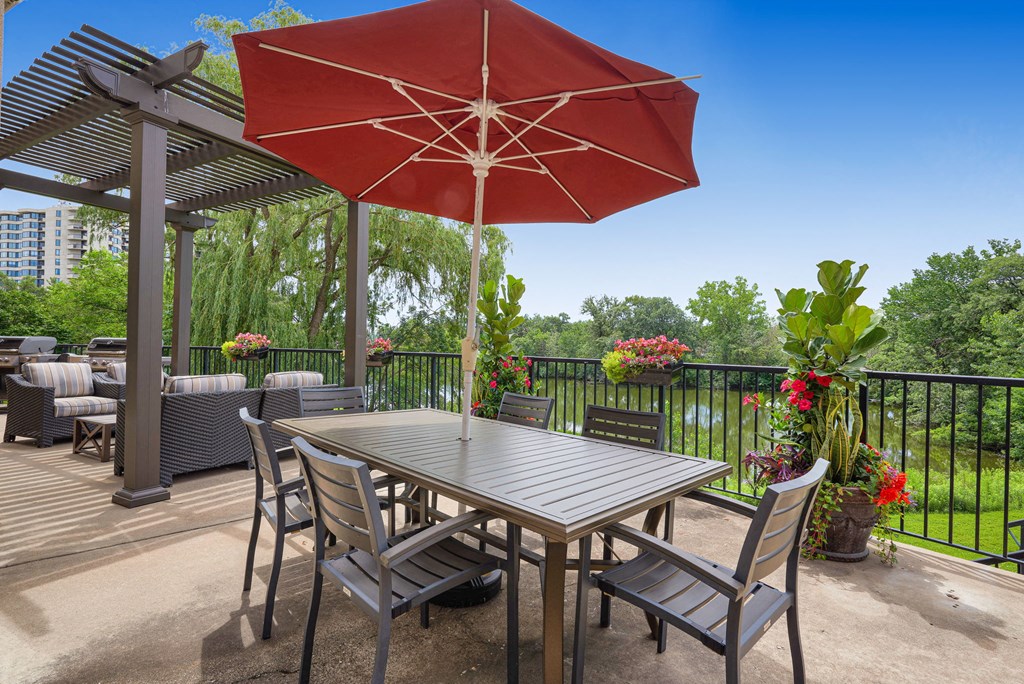 a patio with a table and chairs and a red umbrella