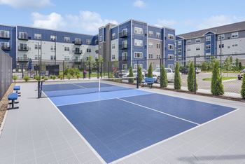 A tennis court is surrounded by apartment buildings at Lochner Apartments, Minnesota