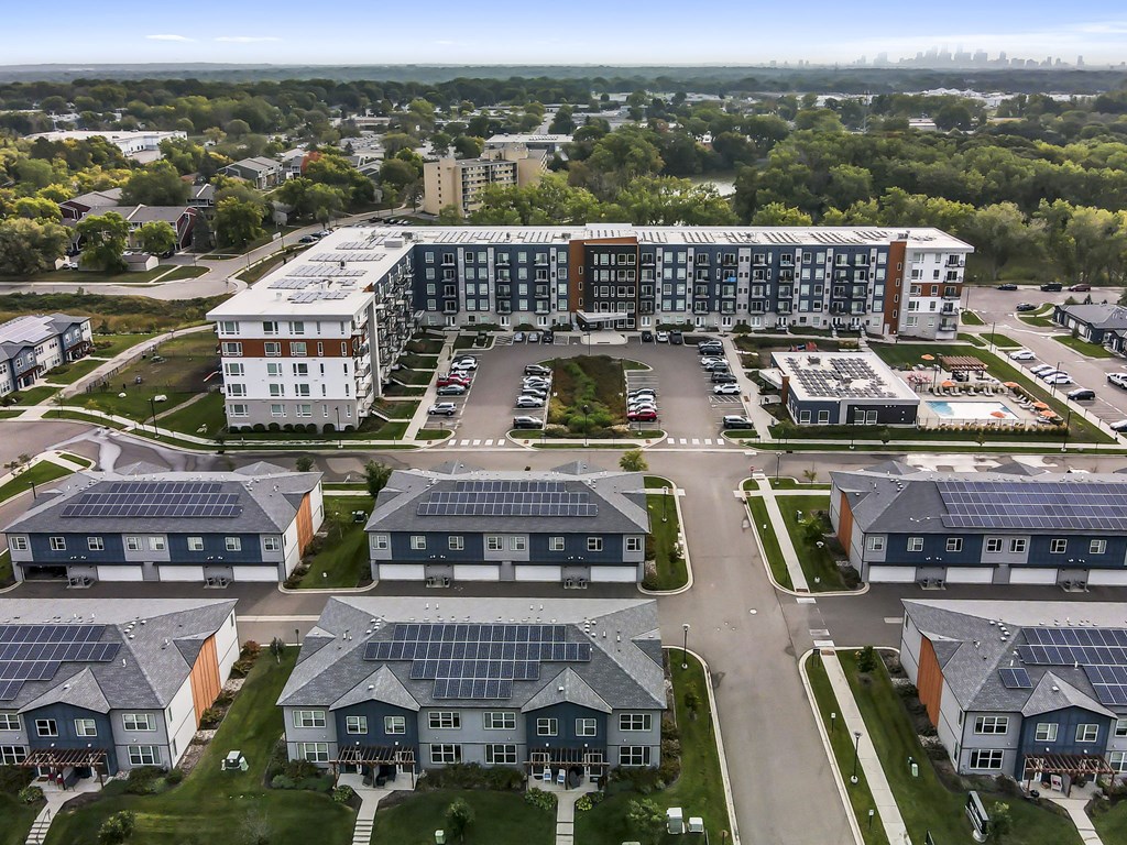 an aerial view of a large apartment complex with a parking lot and trees in the background