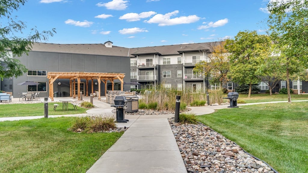 A building with a wooden roof is surrounded by grass and trees.