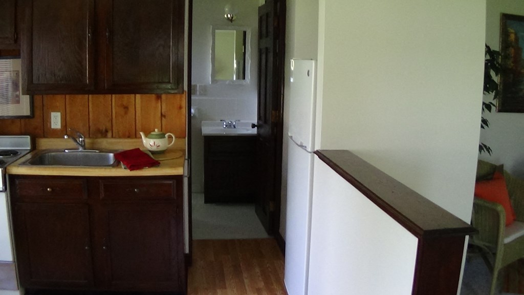 a kitchen with a sink and a refrigerator      and a hallway