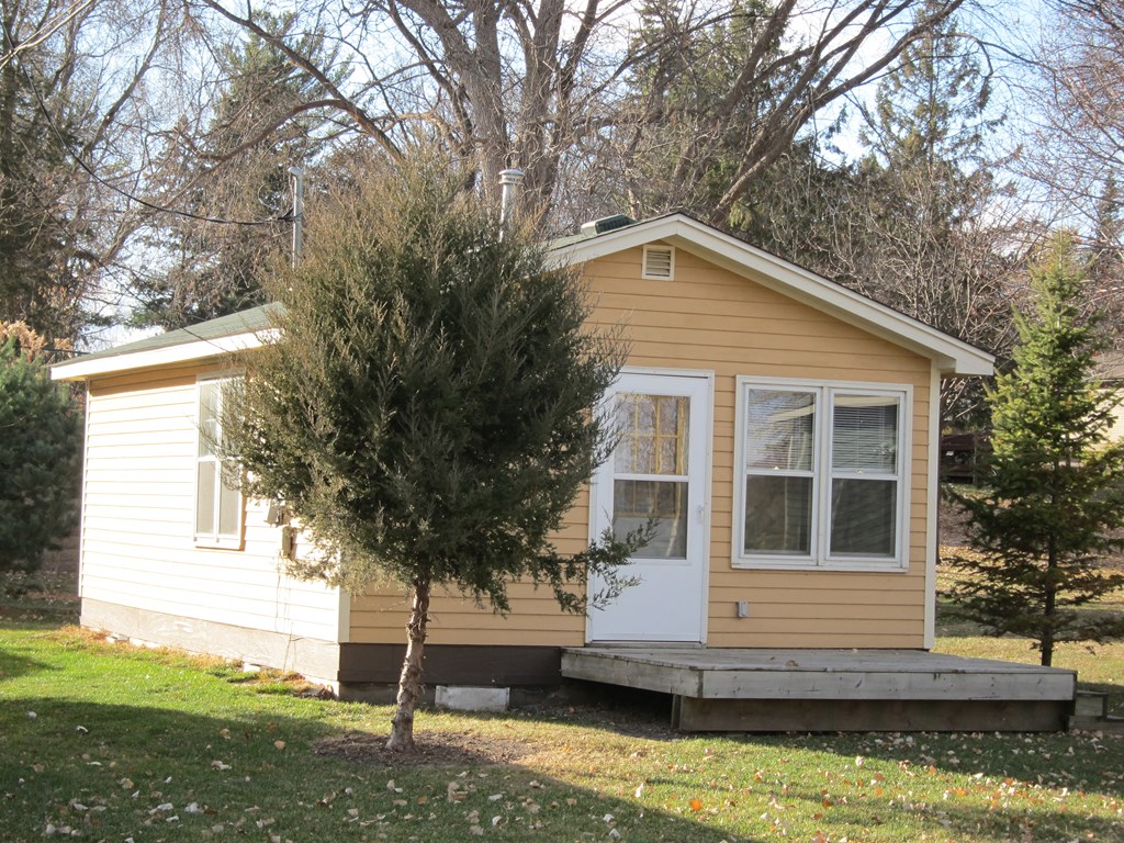 a small yellow house with a tree in front of it