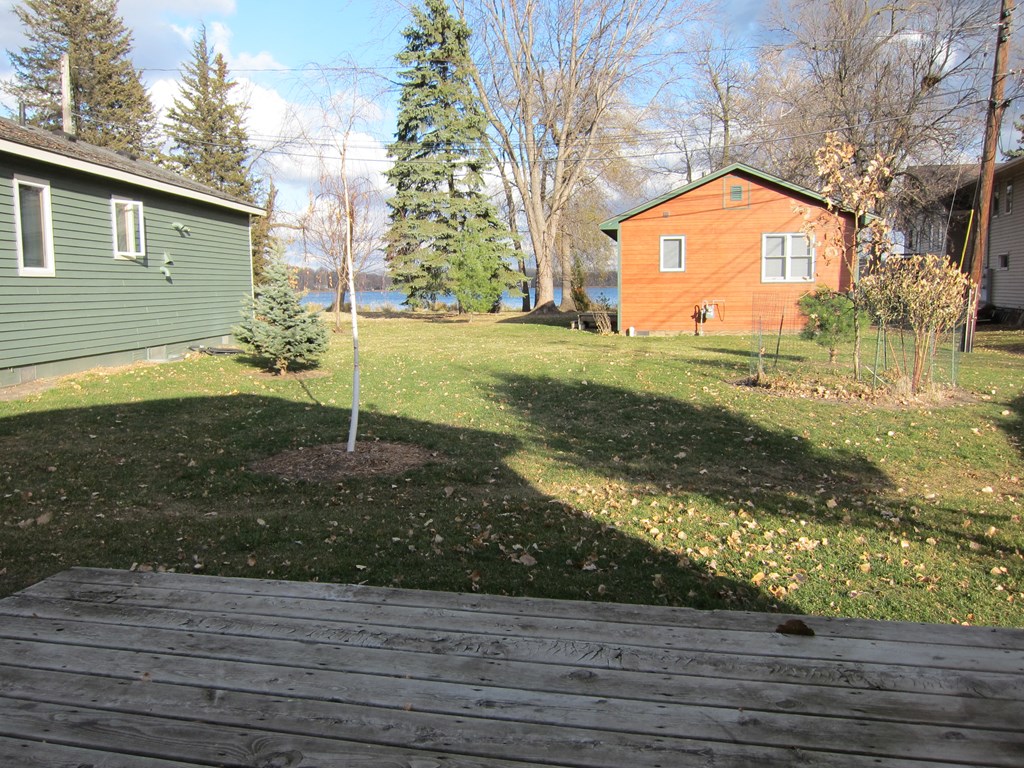 a view of a backyard with a wooden deck and a small tree