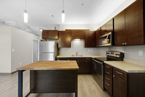 A kitchen with a wooden island and stainless steel appliances.