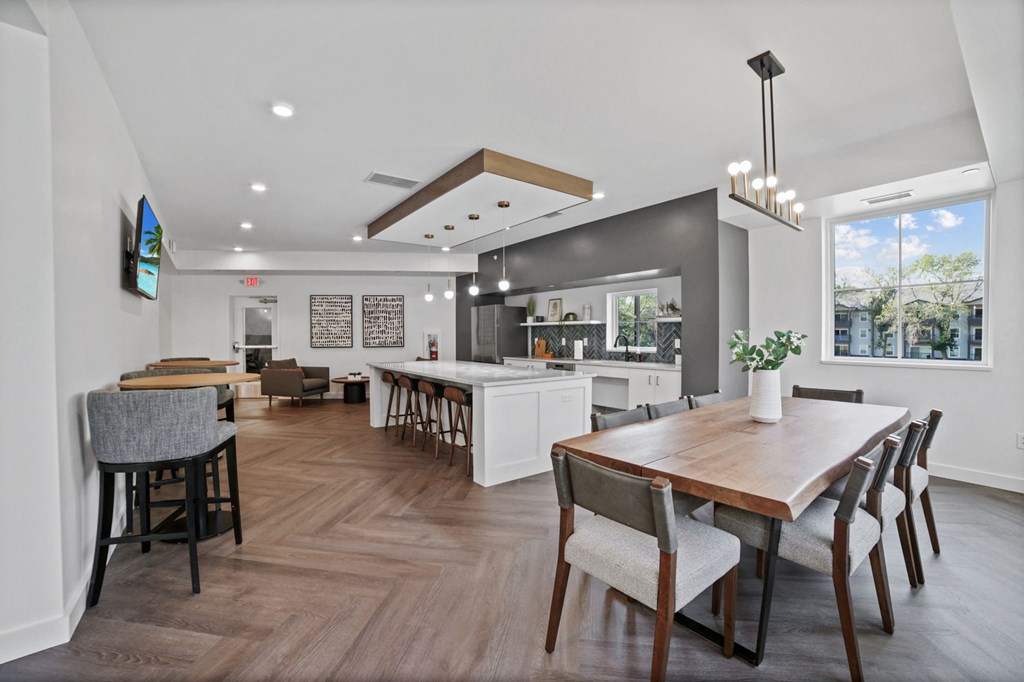 a dining area with a wooden table and chairs and a kitchen in the background