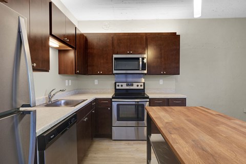 A kitchen with a wooden table and stainless steel appliances.