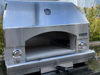 a stainless steel pizza oven sitting on the ground