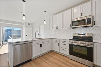 A modern kitchen with white cabinets and stainless steel appliances at Lochner Apartments, White Bear Lake, Minnesota