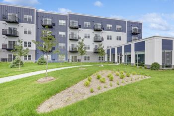 A modern apartment complex with a well-maintained lawn in front at Lochner Apartments, Minnesota, 55110