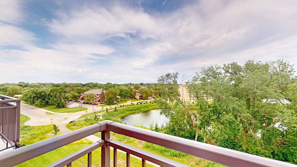 the view from the balcony of a condo with a pond and trees