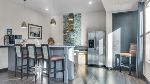 A kitchen with a bar area and a refrigerator with a glass door.