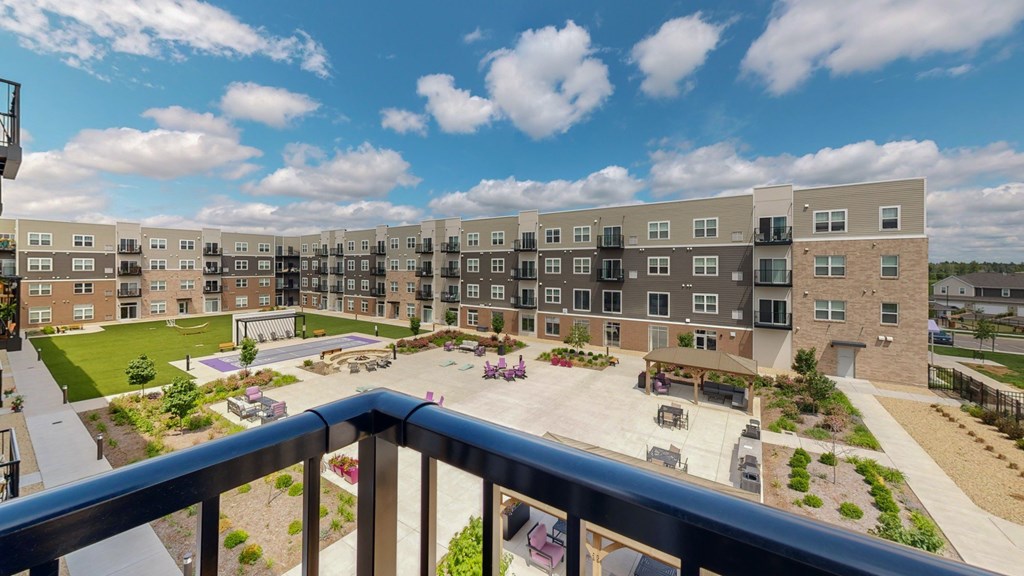 A view of a courtyard from a balcony with apartment buildings in the background.