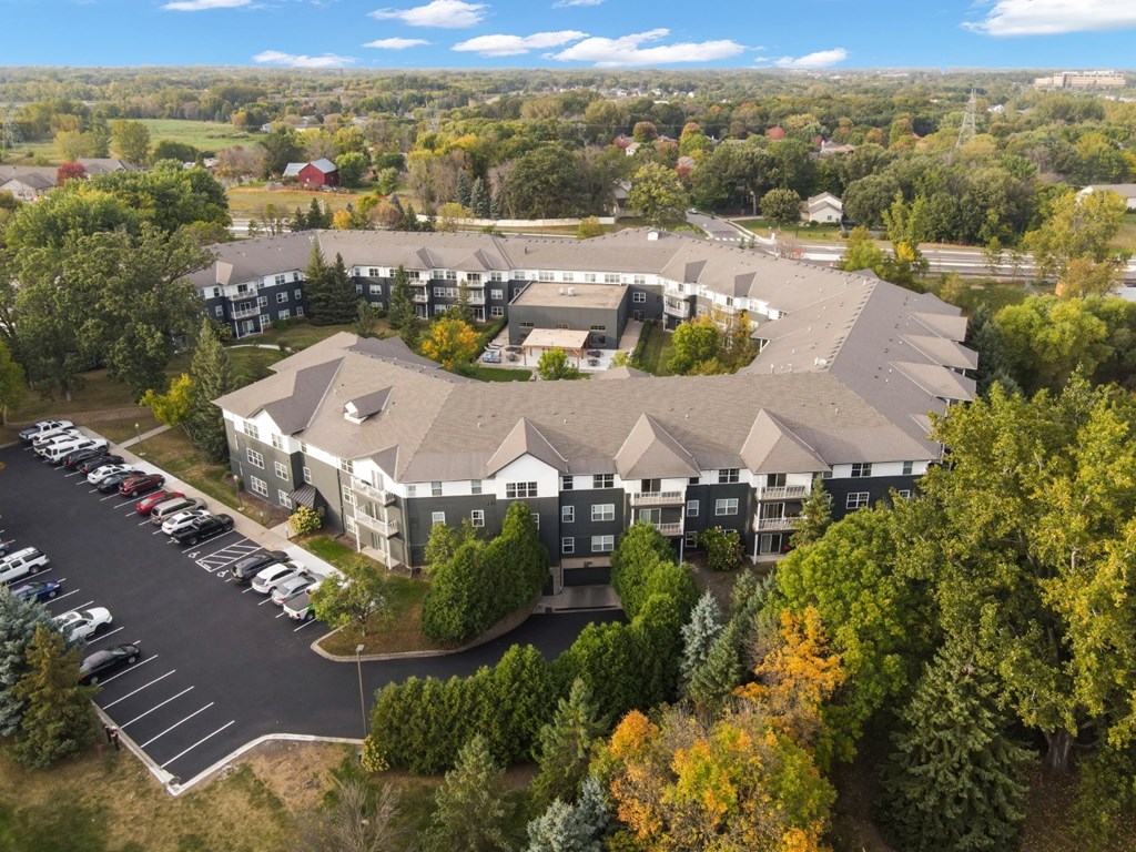 A large building surrounded by trees and a parking lot.