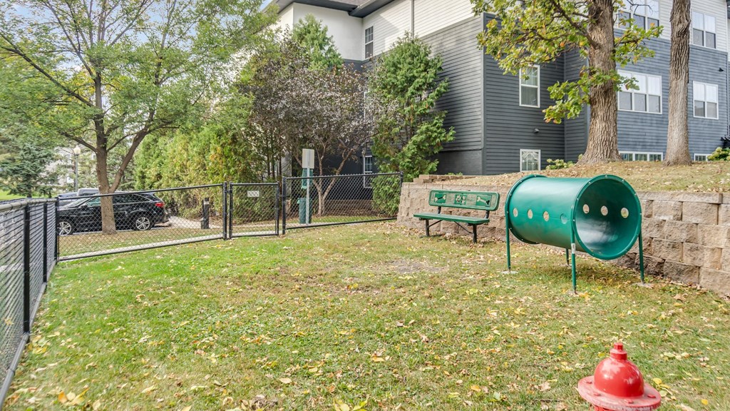 A playground with a green slide and a red fire hydrant.