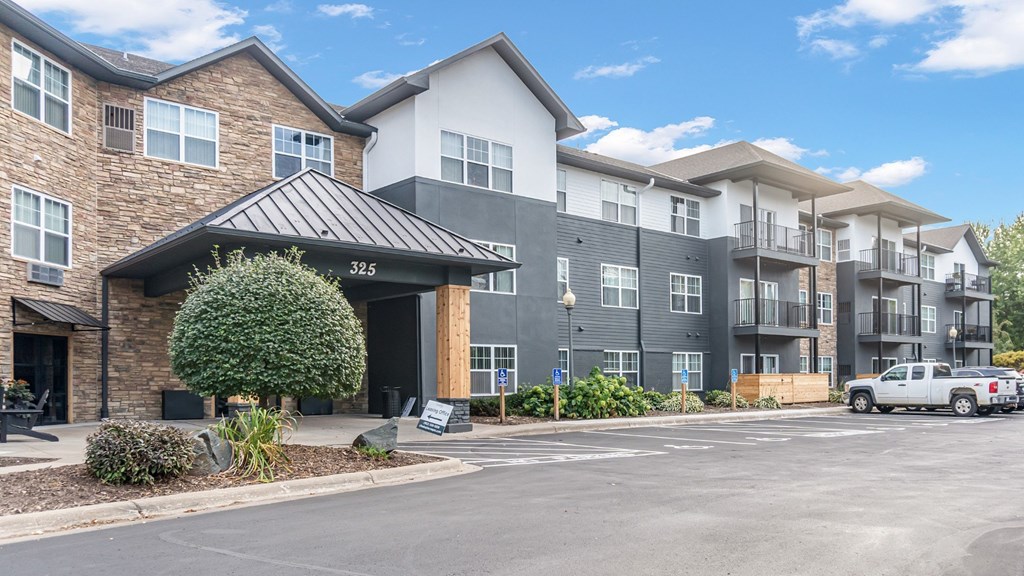 A large apartment complex with a parking lot in front.