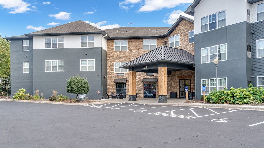 A parking lot in front of a building with a black awning.