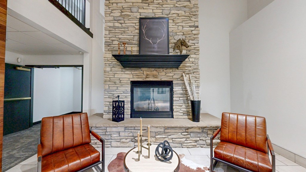A living room with a stone fireplace and two brown leather chairs.