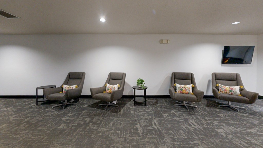 A row of grey chairs with cushions are lined up in a waiting room.