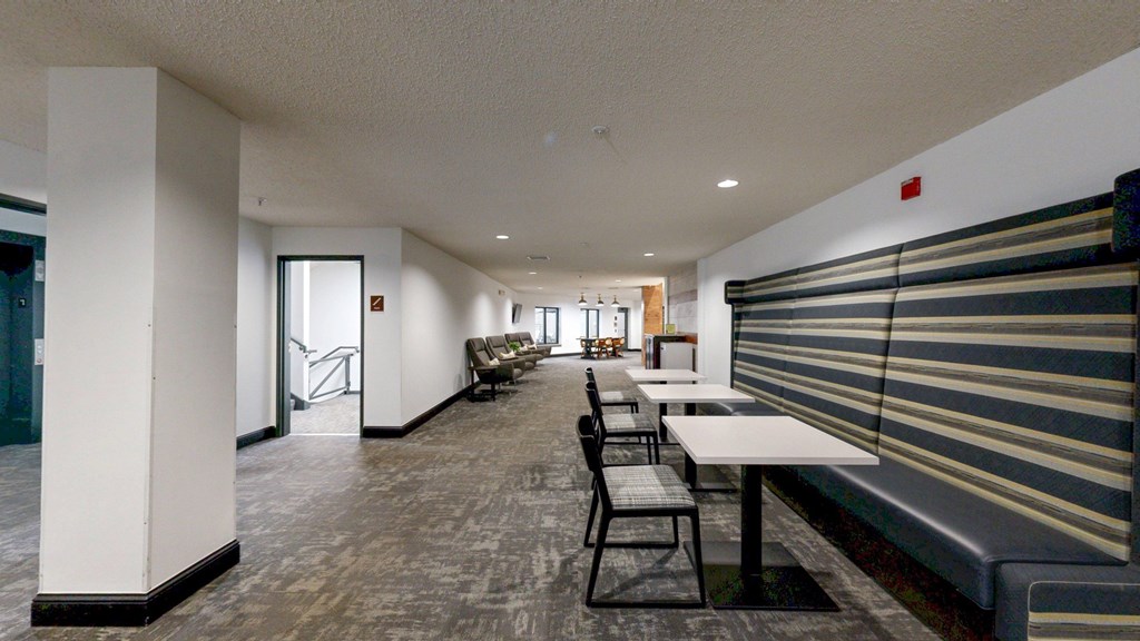 A long white table with chairs is in a room with a bench and a window.