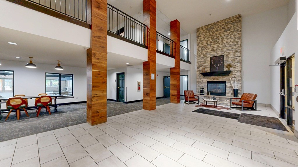A spacious living room with a stone fireplace and a balcony.