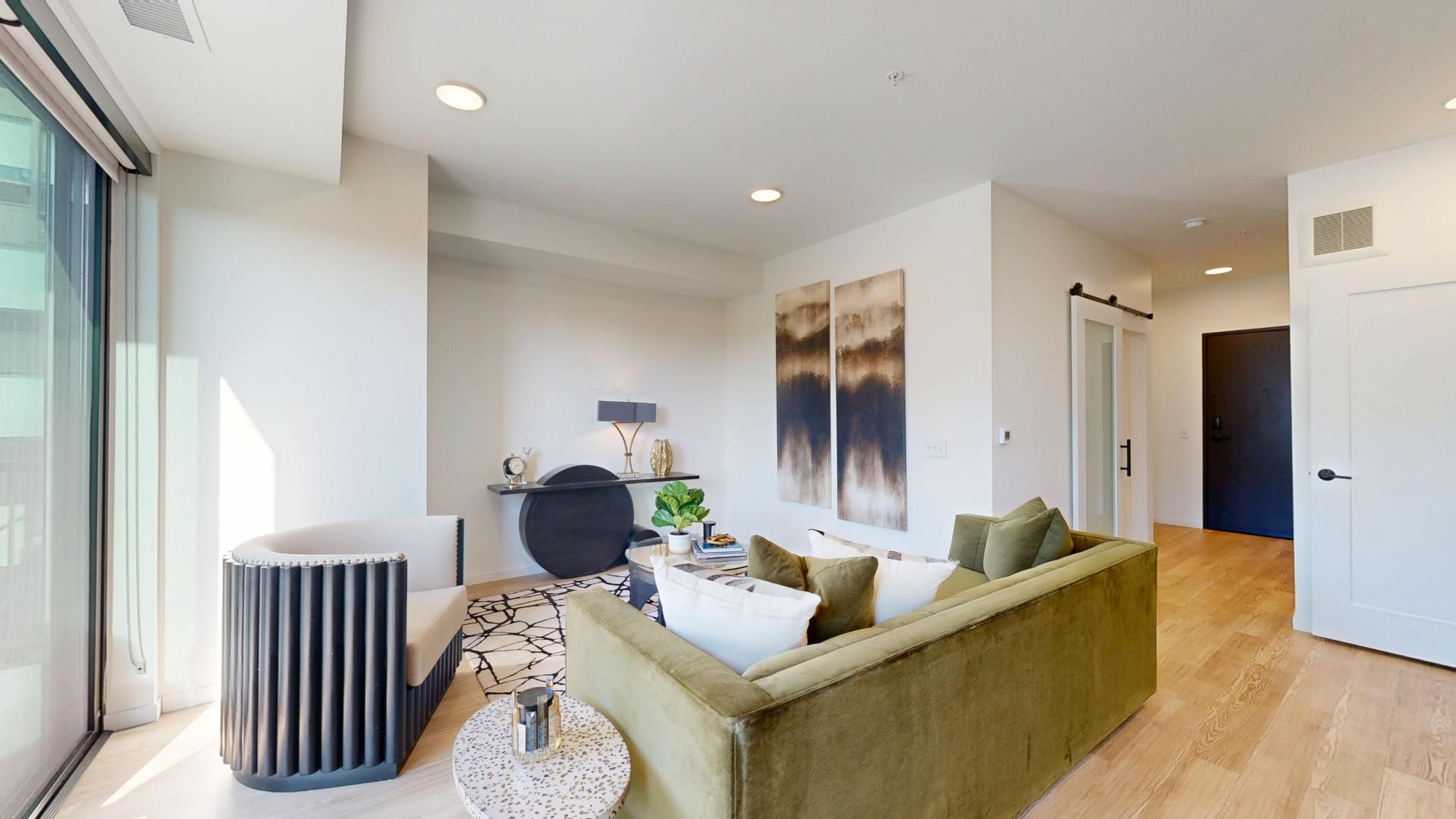 A modern living room with a green couch and a large abstract painting on the wall.