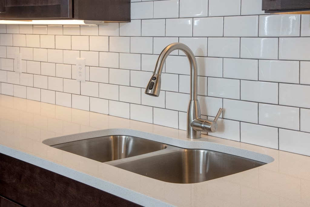 quartz countertops and tile backsplash and undercabinet lighting