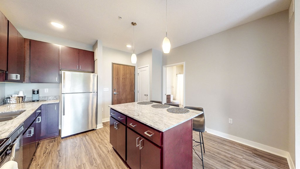 a kitchen with a marble counter top and a stainless steel refrigerator