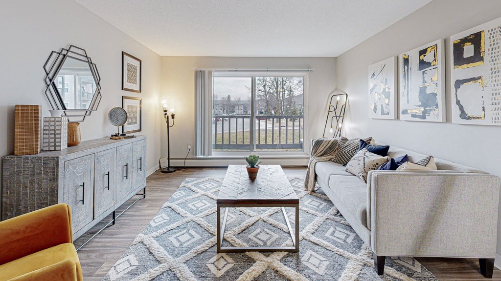 a living room with couch, table and large sliding glass door to balcony