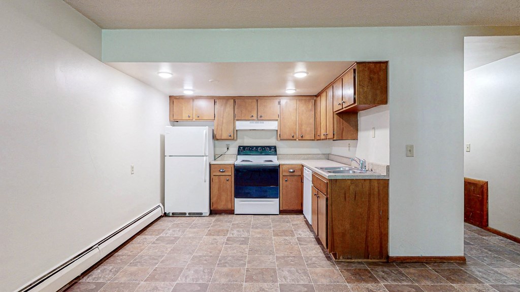 an empty kitchen with white appliances and wooden cabinets