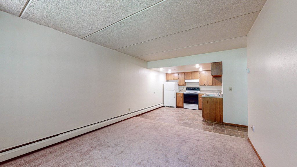 an empty living room and kitchen with white walls