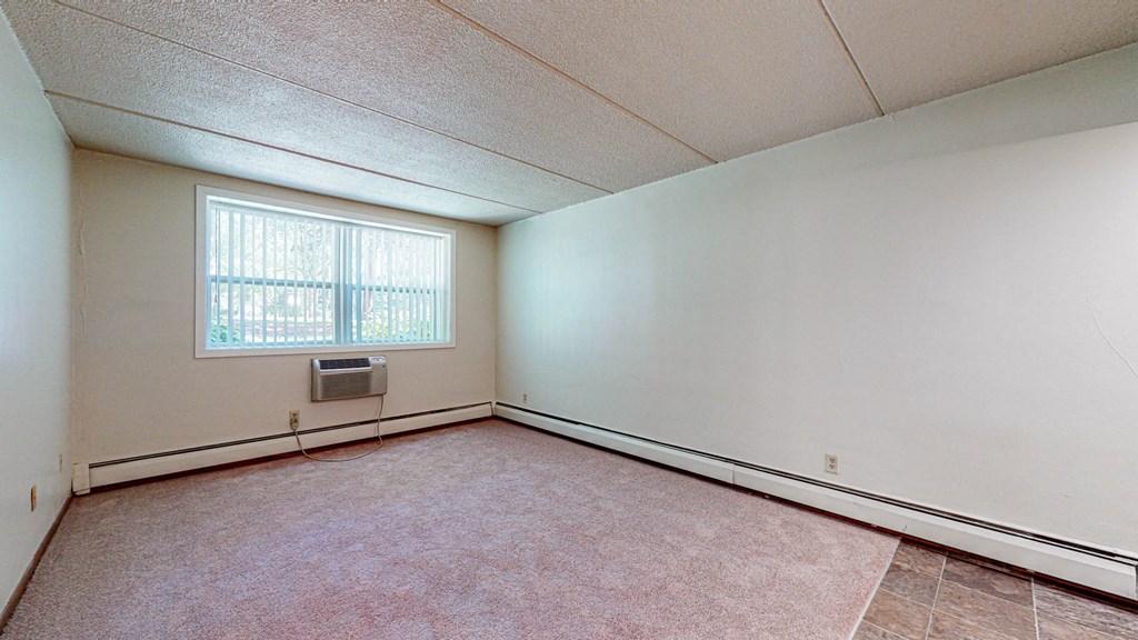 the living room of an empty house with a window and white walls