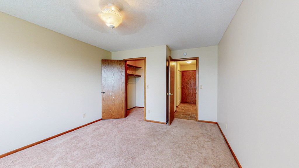 an empty room with carpet and a door to a closet
