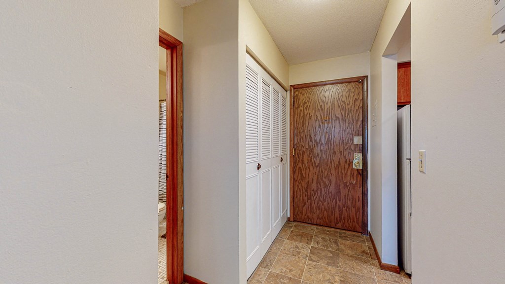 a hallway with a wooden door and a door to a closet