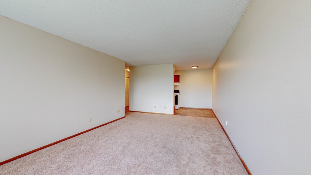 an empty living room with white walls and carpet