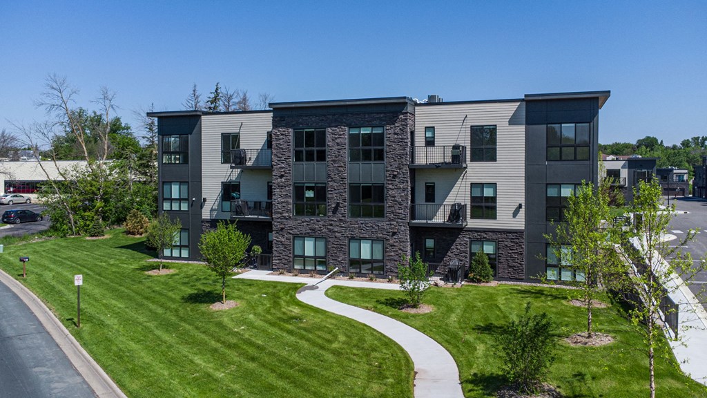 an apartment building with green grass and a sidewalk