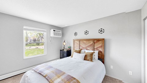 A bedroom with a large bed and a window overlooking a green lawn.