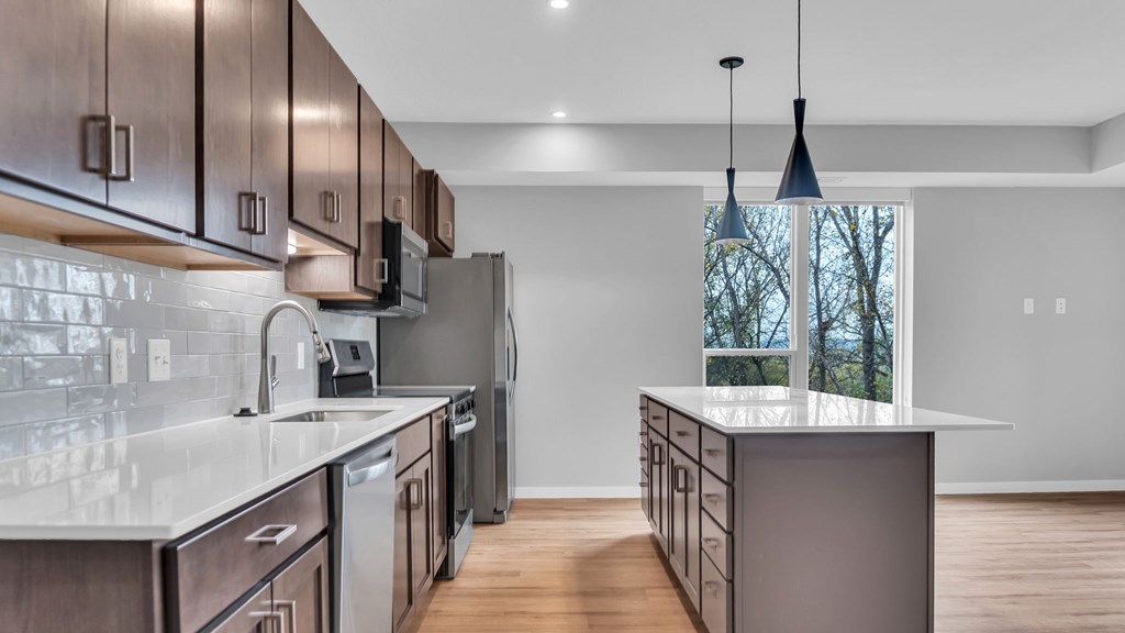 A modern kitchen with dark wood cabinets and stainless steel appliances.