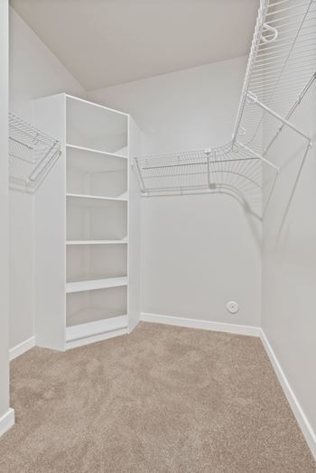 A white closet with shelves and a carpeted floor at Lochner Apartments, White Bear Lake, 55110