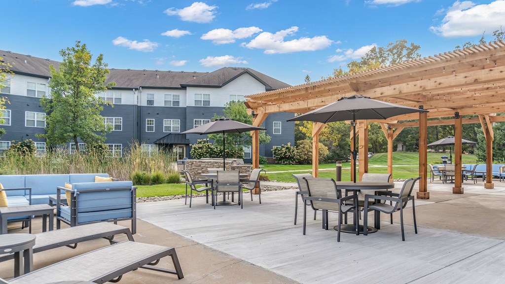 A patio with a table and chairs under a wooden pergola.