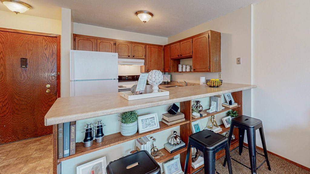 a kitchen with a bar and stools and a refrigerator