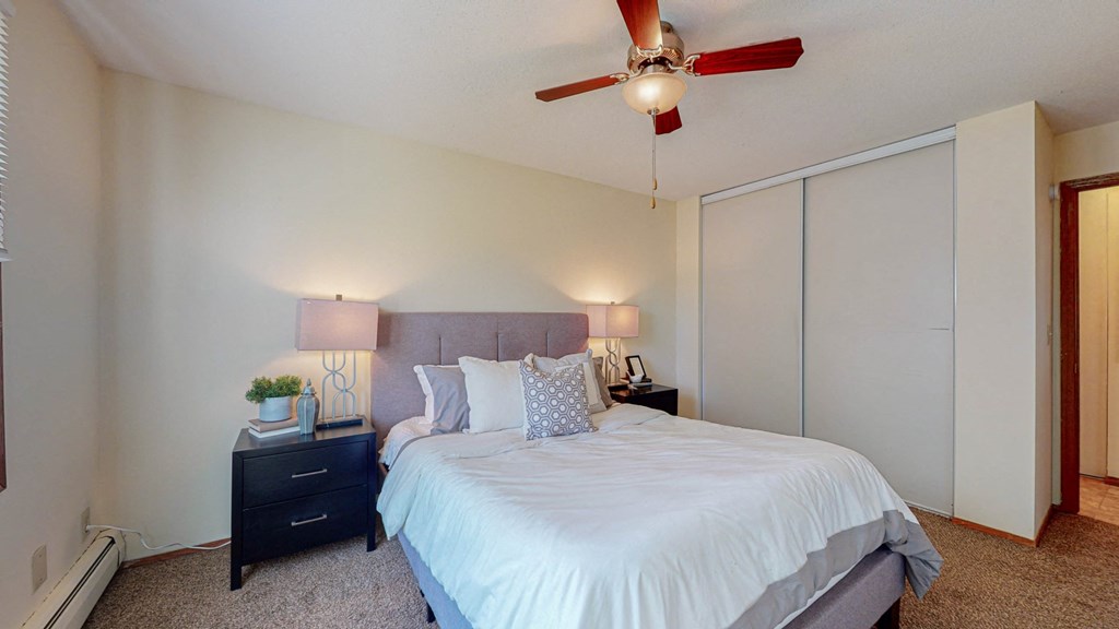 a bedroom with a large white bed and a ceiling fan